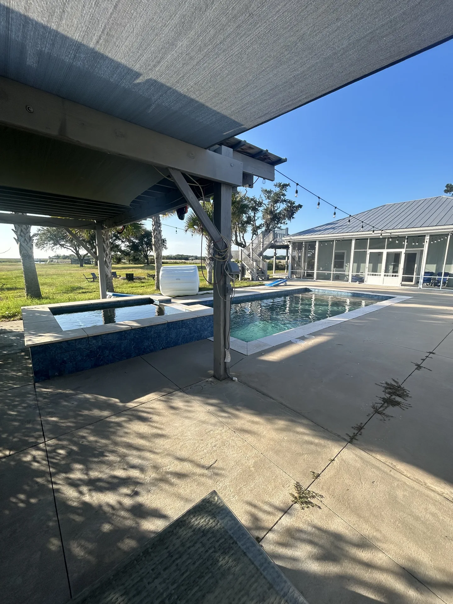 View from under the pergola across the spa and pool toward the main house
