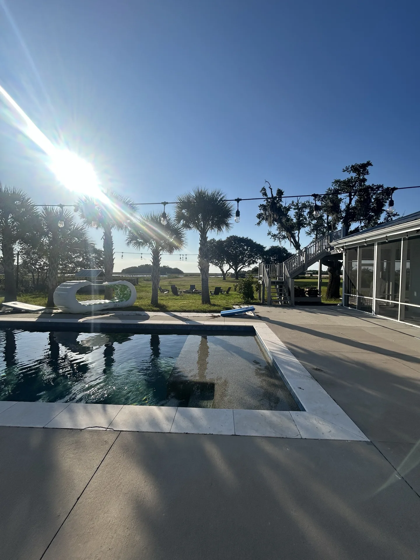 Sweeping golden-hour panorama from the pool with palmettos and the vast marsh beyond