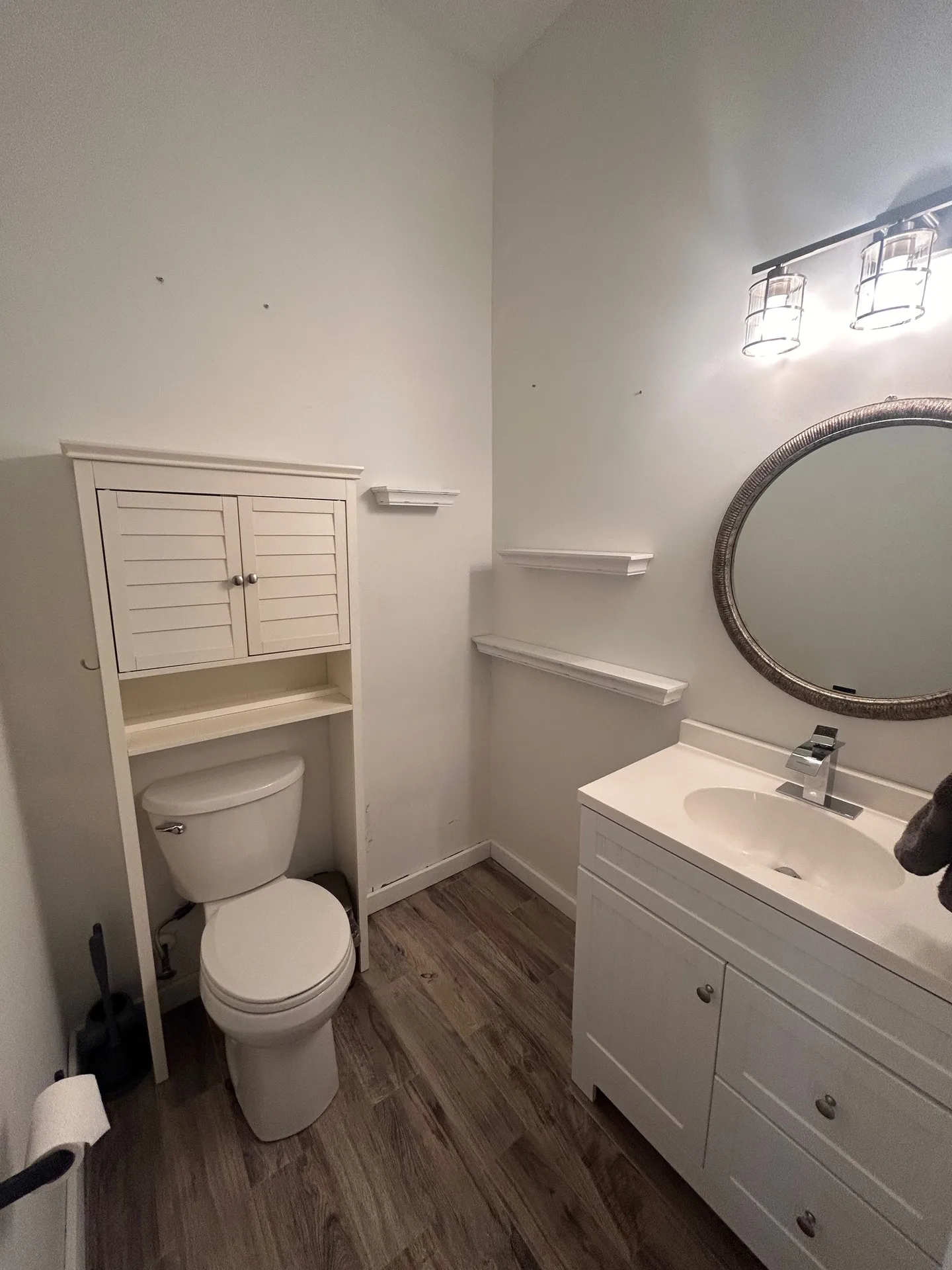 Cottage half bath with white vanity, distressed wood mirror, and cage-style lights