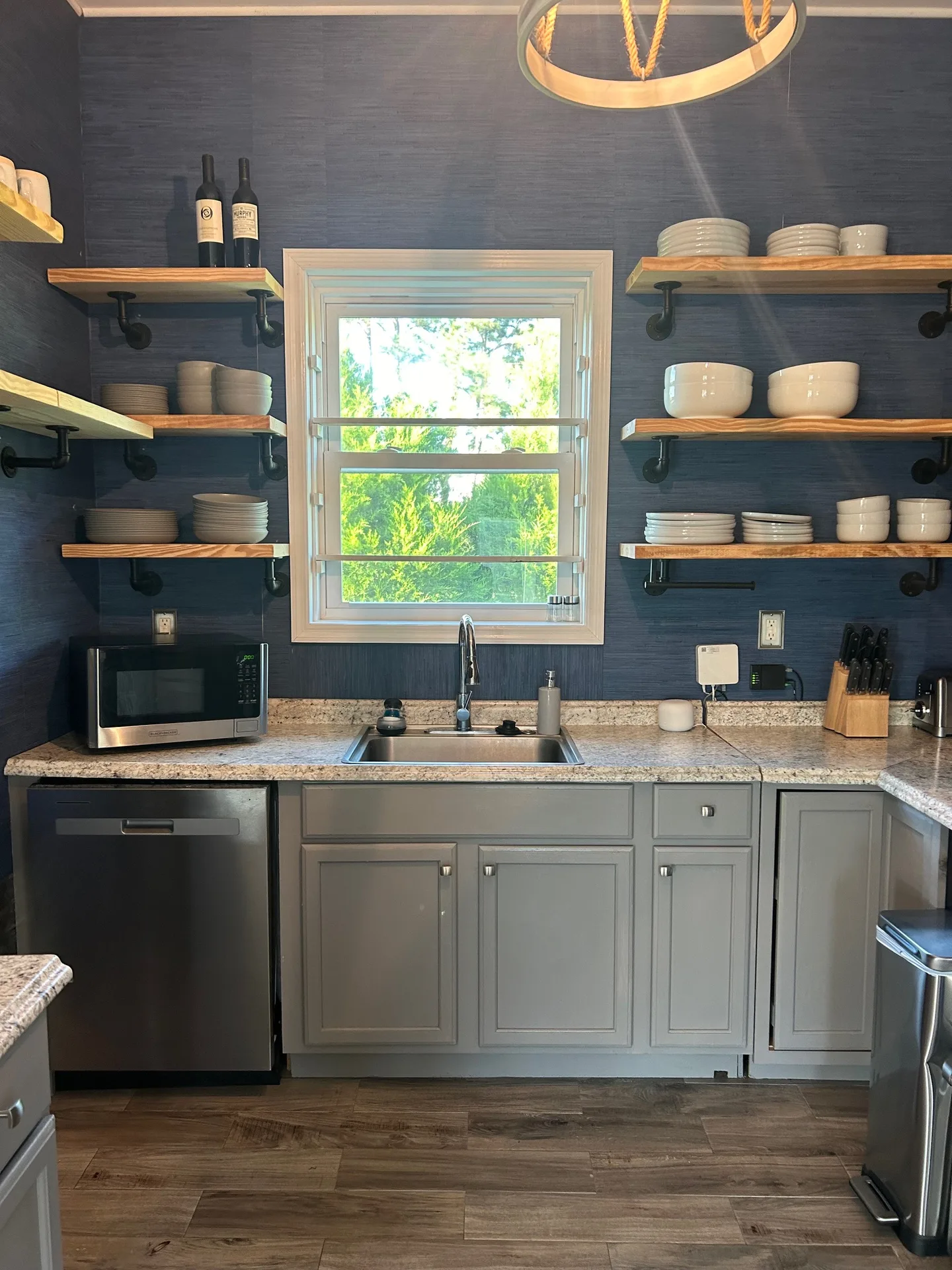 Kitchen sink wall with live-edge shelves flanking window and white ceramic dish display