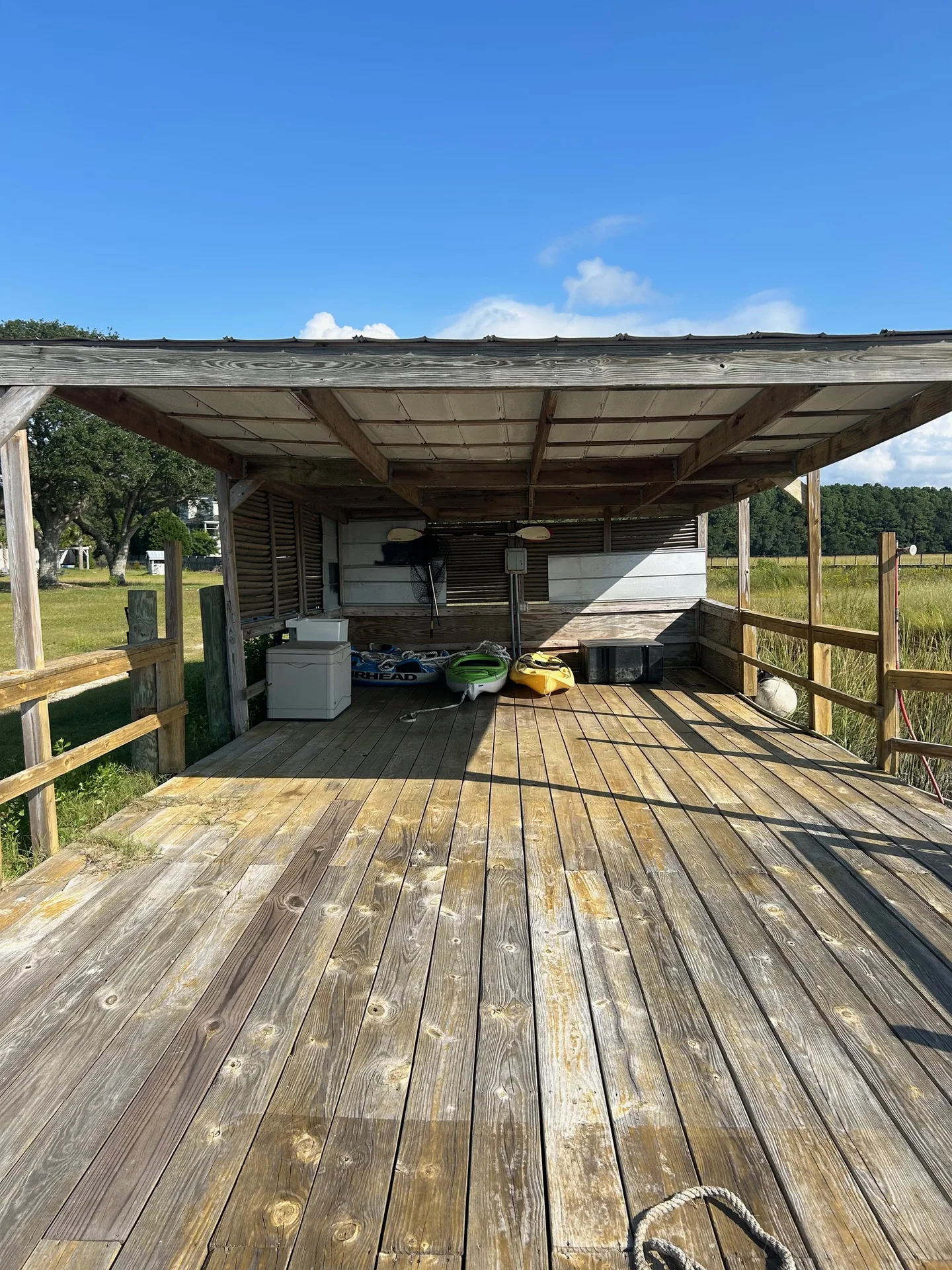Boathouse pavilion with kayak storage — yellow and green kayaks with sweeping marsh views