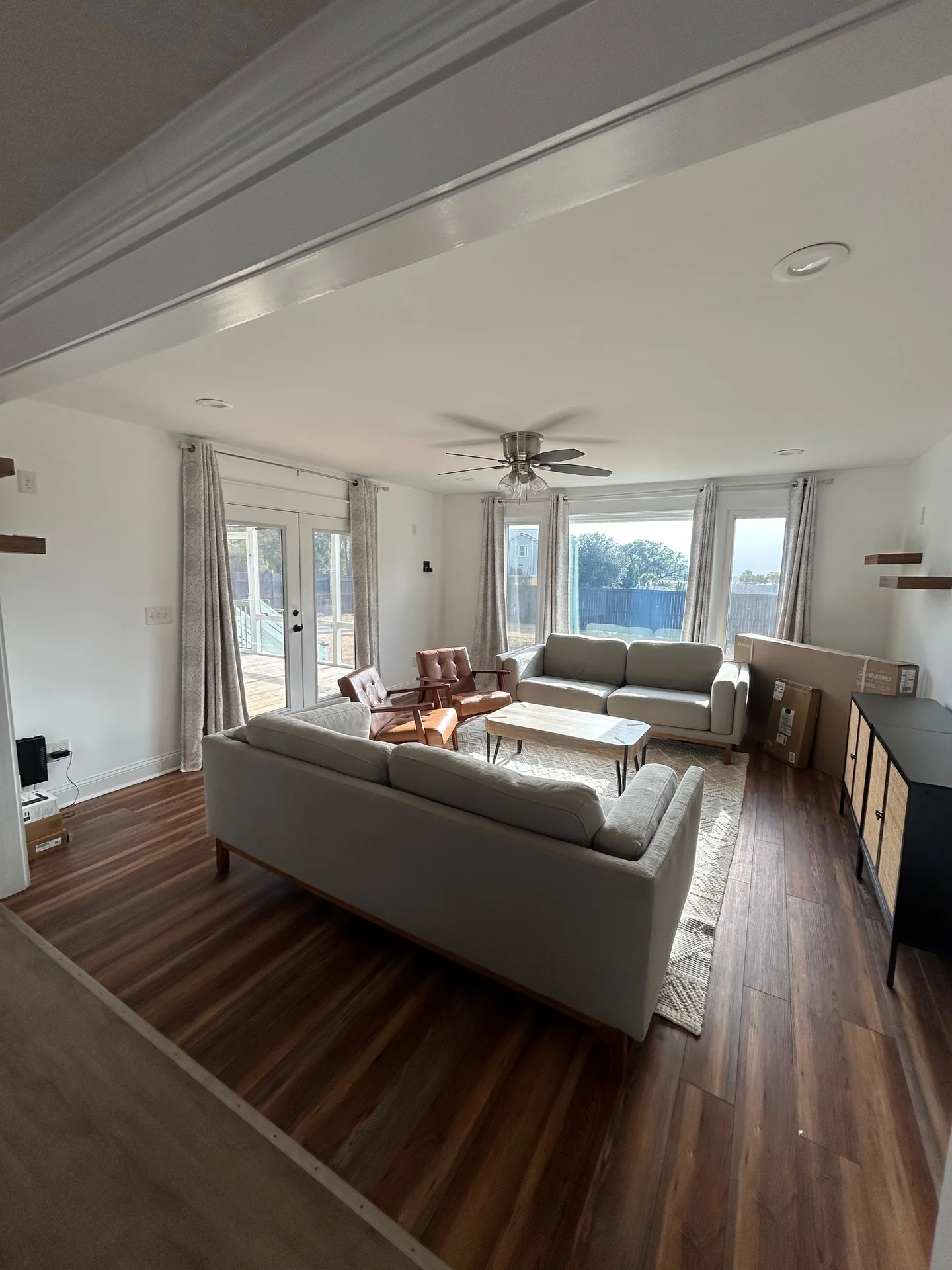 Living room from French door side with navy-framed doors open to deck