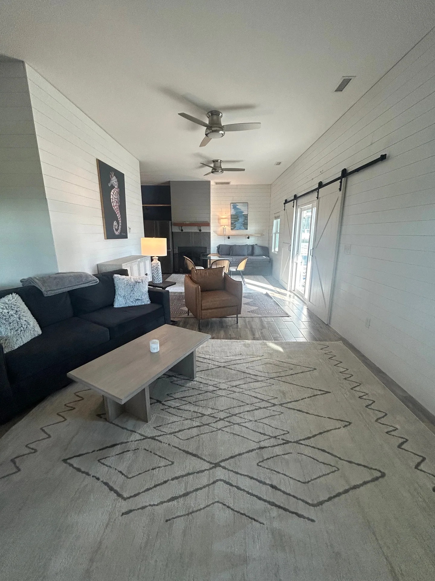 Living room facing barn doors with dual sofas, cognac leather chairs, and Moroccan rug